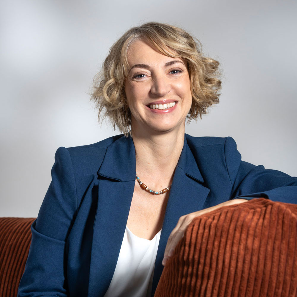 Cinzia Turrini, Konferenzdolmetscherin und Fachübersetzerin, lächelt. Sie ist blond und trägt einen blauen Blazer. (Kleines Bild)